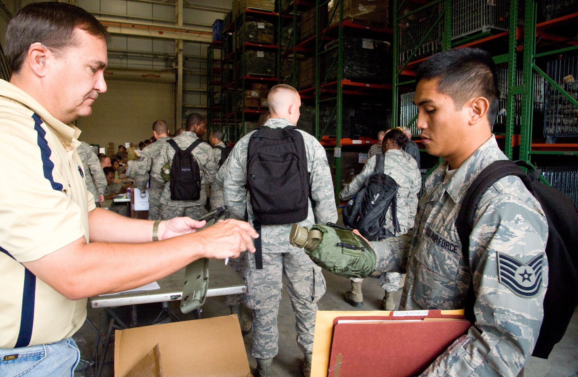 Danny Gilseth, the 512th Airlift Wing’s senior logistics manager, issues Tech. Sgt. Yerkes Tecson, a canteen and web belt during a mobility line Sept. 27, 2012, on Dover Air Force Base, Del. Tecson will join a group of other Reserve aerial porters, from the 46th Aerial Port Squadron, for a six-month deployment to the Transit Center at Manas, Kyrgyz Republic. (U.S. Air Force photo/Adrian Rowan)