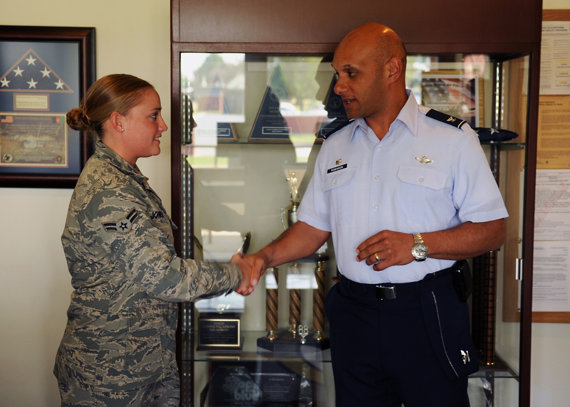 Col. Brian Robinson, 19th Airlift Wing commander, congratulates Airman 1st Class Michelle Johnson, a 19th Communications Squadron Cyber Systems Apprentice, for her selection as the Combat Airlifter of the week Sept. 24, 2012, at Little Rock Air Force Base, Ark. Johnson, a Dothan, Ala. native, reduced trouble ticket queues for her squadron by 20 percent and installed required drivers and software for the 19th Equipment Maintenance Squadron enabling the electronic storage of engine control data. (U.S. Air Force photo by Staff Sgt. Jessica Condit)