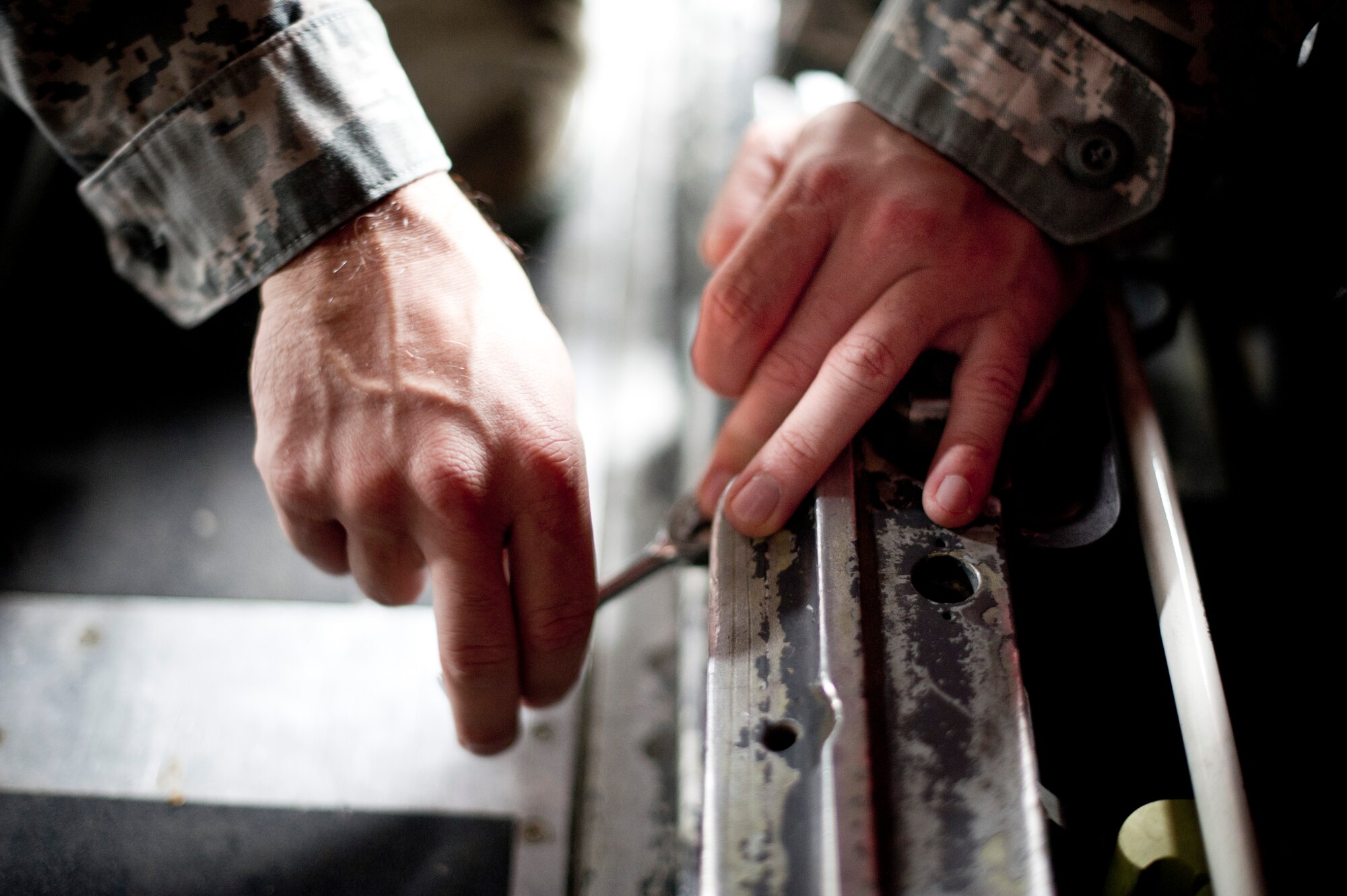 YOKOTA AIR BASE, Japan -- Staff Sgt. Christian Petersen, 374th Aircraft Maintenance Squadron, uses a ratchet to remove mount bolts from cargo rails Sept. 25, 2012, at Yokota Air Base, Japan. Removing the rails can take up to two hours. Stuck bolts are one of the major hindrances that can make this task more timely. (U.S. Air Force Photo by Staff Sgt. Stacy Moless)