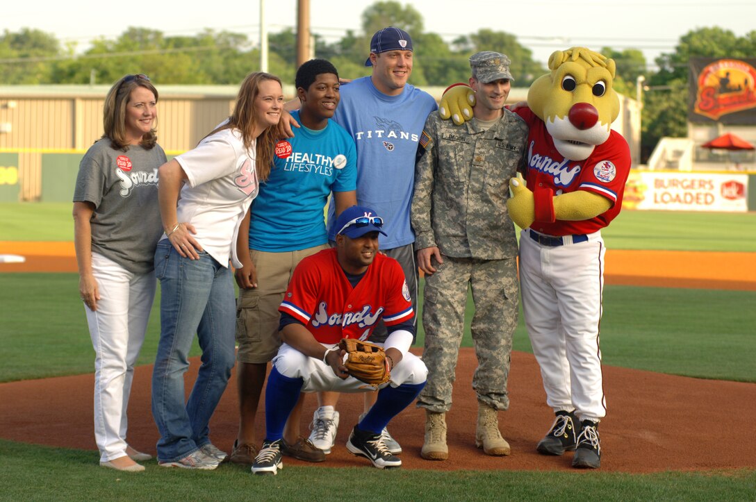 Maj. Patrick Dagon poses with others who also threw first pitches and is standing in uniform next to Ozzie, the Sounds' mascot. (USACE photo by Lee Roberts)