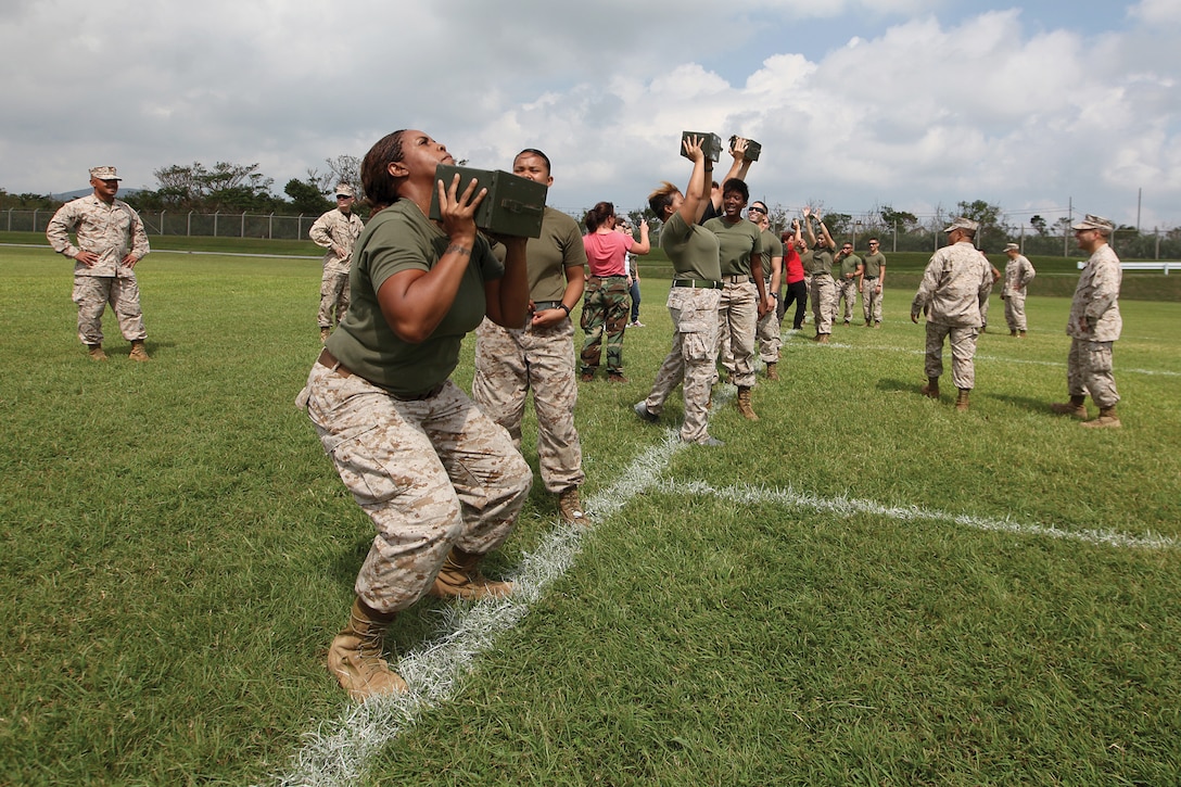 Marine spouses lift ammunition cans during a modified combat fitness test as part of the 3rd Marine Logistics Group’s Jane Wayne day at Camp Hansen Sept. 21. The modified CFT featured ammunition can lifts and a shortened maneuver under fire lane. Marines who volunteered for the event were with various units within 3rd MLG, III Marine Expeditionary Force. 