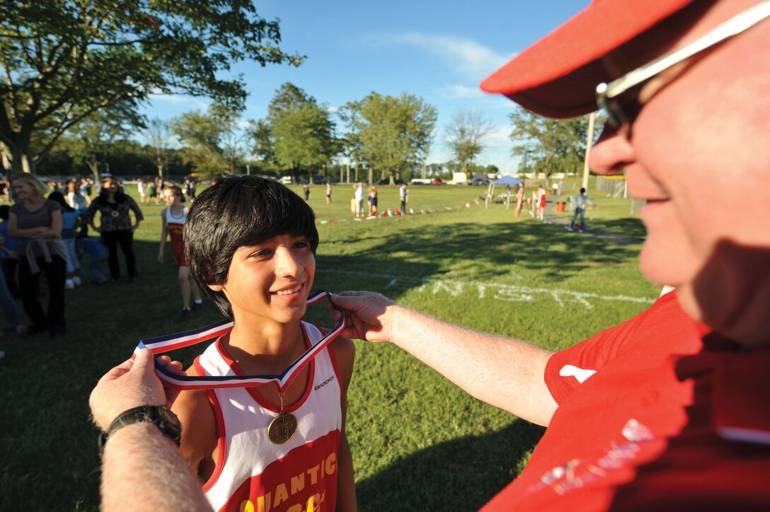 Dan Mulhern, Quantico Middle/High School assistant principal, presents the third place medal to Tyler, Quantico MHS ninth grade runner, during their cross country invitational at John H. Russell Elementary School on Sept. 11. As a team, Quantico, came in fifth place in the invitational.