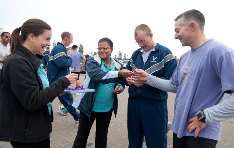 VANDENBERG AIR FORCE BASE, Calif. – Sandra Metzdorf, Vandenberg Spouses Club president, and Amanda Craycraft, VSC scholarship chair, hand out purple ribbon pins in support of Domestic Violence Awareness Month after the wing run here Friday, Sept. 28, 2012. The Vandenberg Spouses Club is a charitable and social organization dedicated to promoting a sense of belonging, support and voice for the Vandenberg spouses community. (U.S. Air Force photo by Senior Airman Lael Huss)
