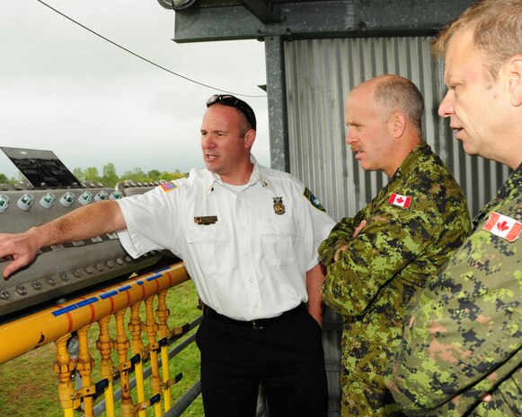 Assistant Fire Chief Aaron McLane (left), Niagara Falls Air Reserve Station Fire Emergency Services, demonstrates how training fires are generated from the control tower to Major Rick Dunning (center), 1 Canadian Air Division Fire Marshall for the Royal Canadian Air Force and Warrant Officer Ron Johnson, 8 Wing Canadian Forces Base Trenton, Platoon Fire Chief on September 26, 2012 at the Niagara Falls Air Reserve Station, N.Y.  The Canadians were here to do a comparative analysis between what the U.S. Air Force is using to train their firefighters compared to what Canadian Forces have. (U.S. Air Force photo by Peter Borys)