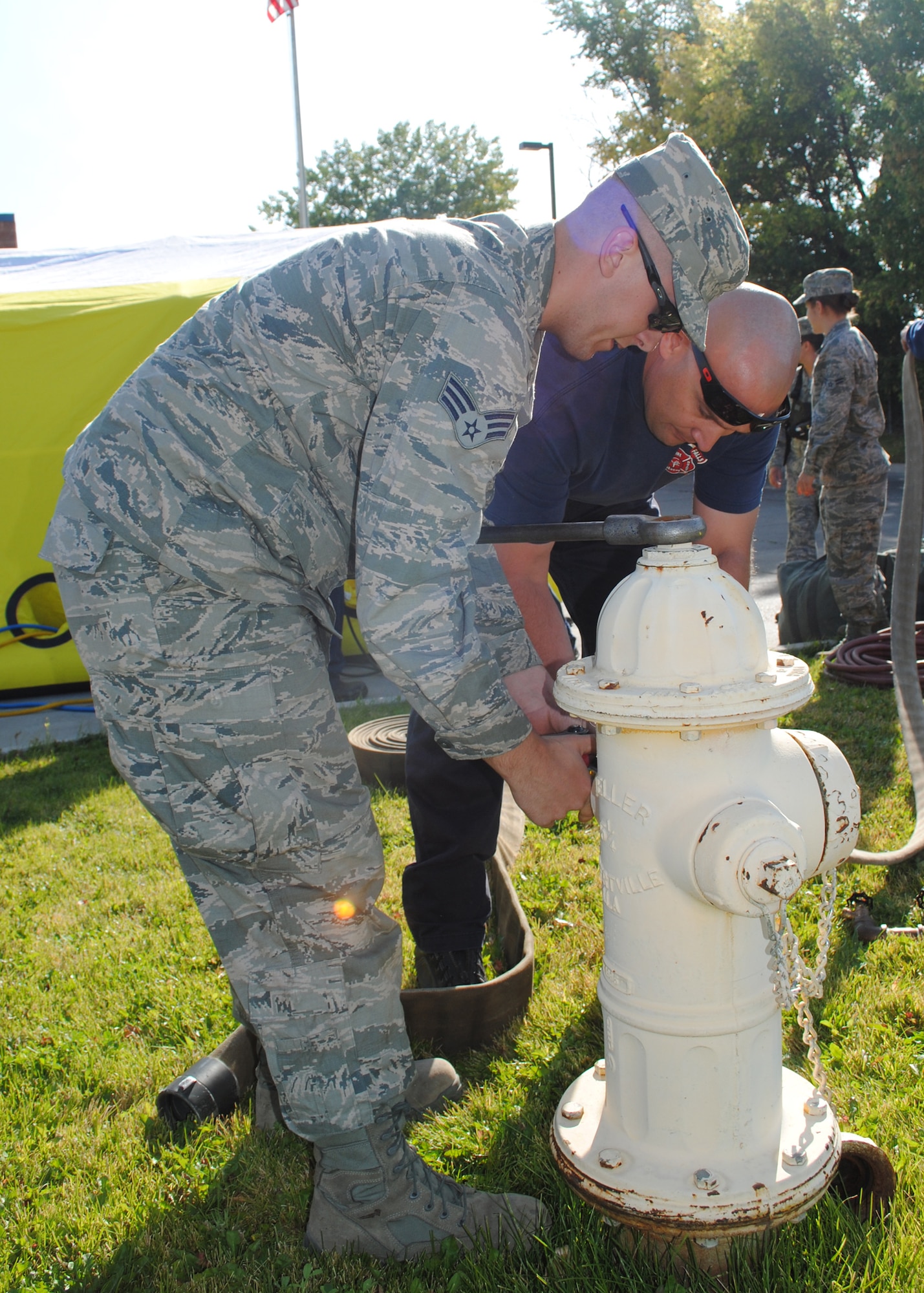 Senior Airman Channing Jones, 341st Civil Engineer Squadron fire fighter, left, connects a hose to a fire hydrant with the help of a member from Great Falls Fire Rescue as they set up equipment to make a wet decontamination tent. More than 20 members of Team Malmstrom participated in a Bio-Detection System Alert exercise at the Great Falls Processing and Distribution Facility on Sept. 20. (U.S. Air Force photo/Airman 1st Class Katrina Heikkinen)