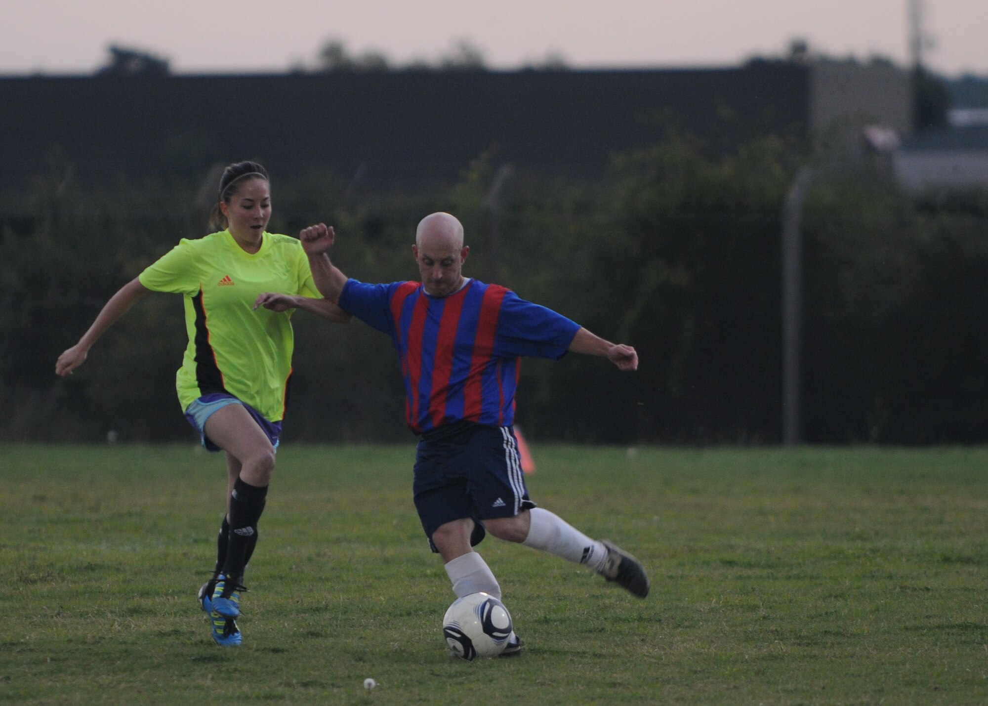RAF MILDENHALL, England – Master Sgt. Lawrence Ballinger, 100th Logistics Readiness Squadron, kicks the ball while being pressured by Amanda Velasco, 100th Civil Engineer Squadron spouse, during an intramural soccer match against the 100th Civil Engineer Squadron Sept. 27, 2012, at RAF Mildenhall, England. (U.S. Air Force photo/Tech. Sgt. Neal X. Joiner)