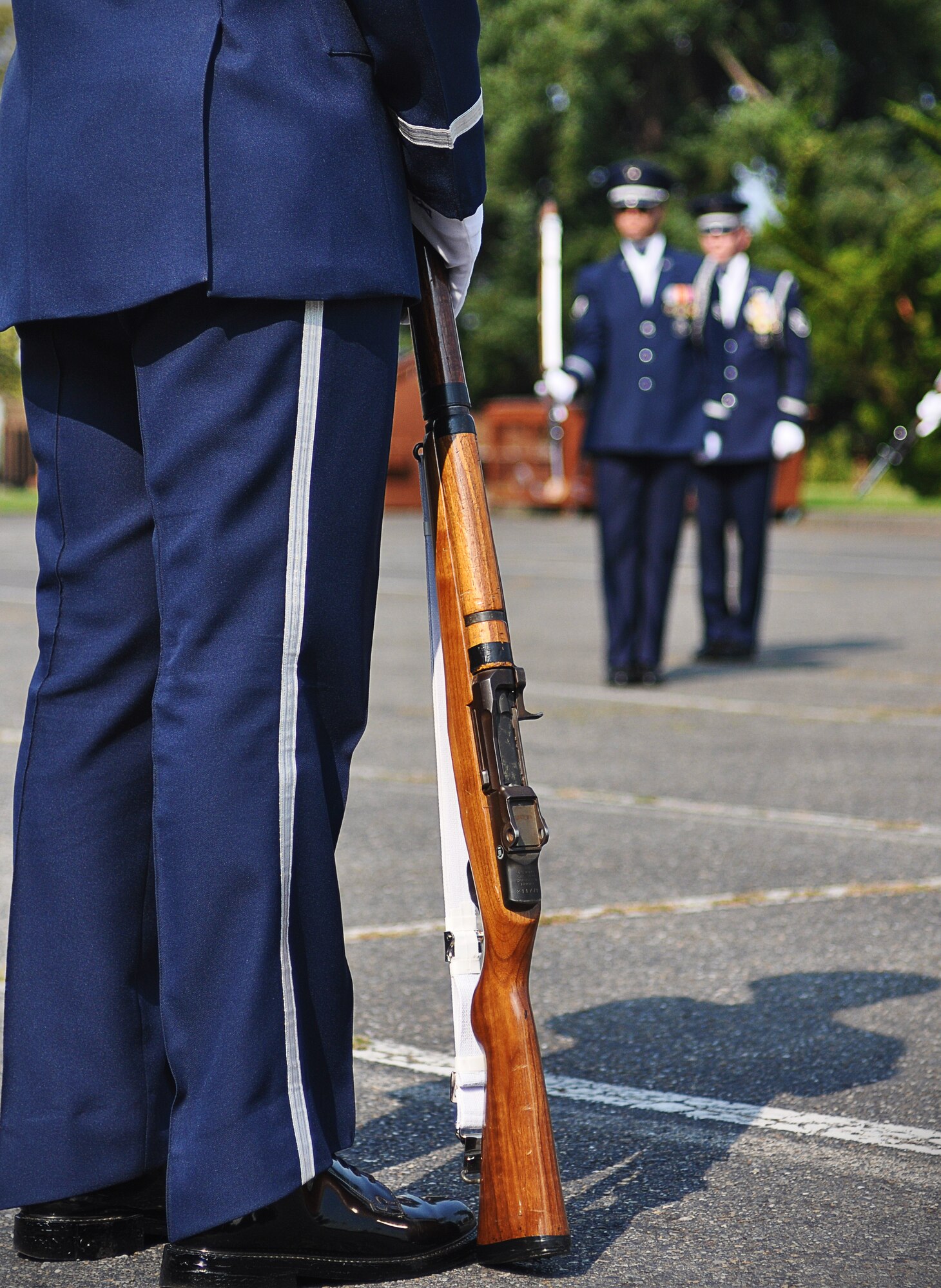 A member of the U.S. Air Force Honor Guard drill team stands with his M-1 Garand rifile at his side as his teammates perform in the background, Sept. 24, 2012 at Joint Base Lewis-McChord, Wash. The team stopped at JBLM on their tour around the country and performed many demonstrations around the area. (U.S. Air Force photo/Staff Sgt. Sean Tobin)