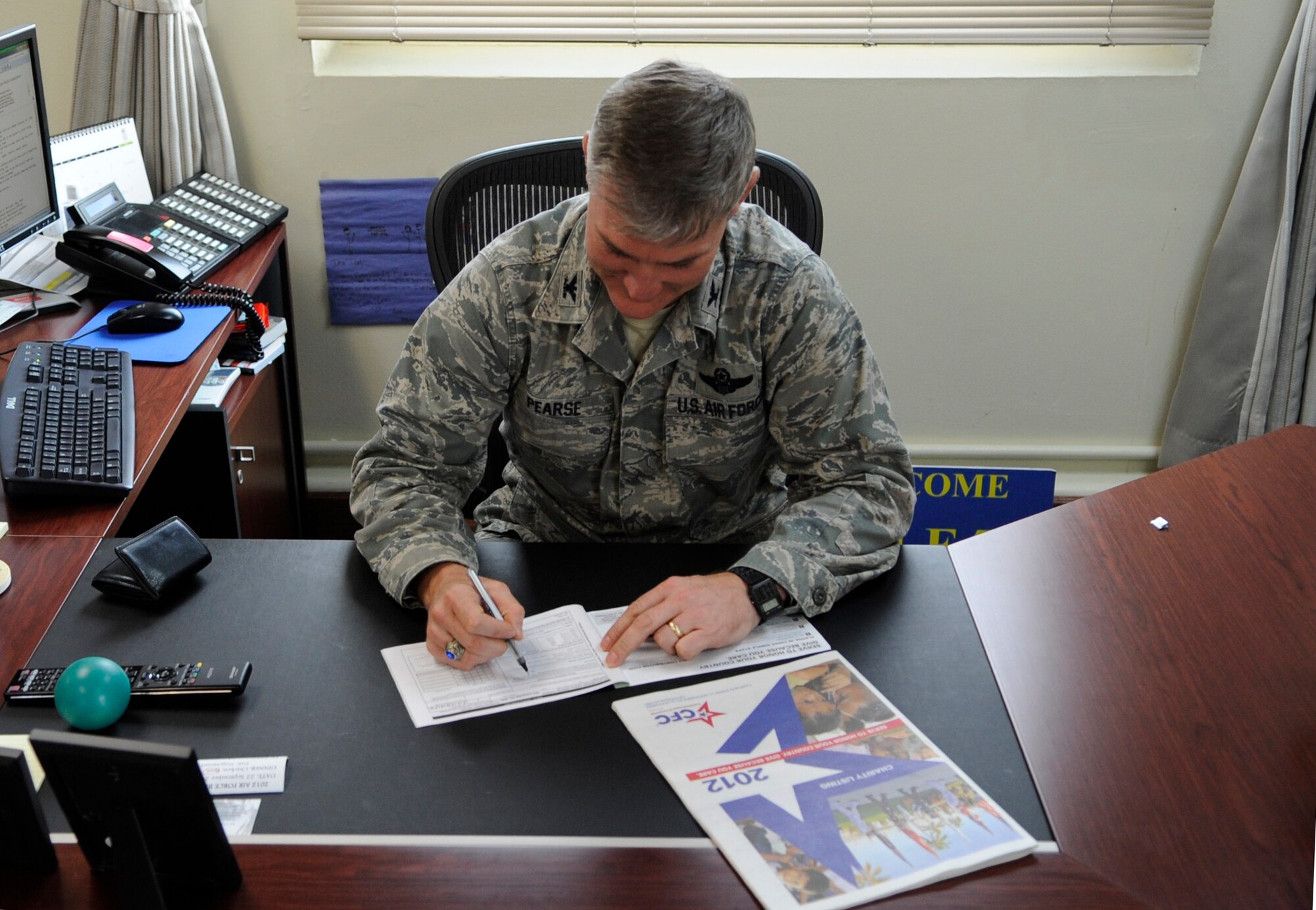 Col. John Pearse, 8th Fighter Wing commander, signs the first Combined Federal Campaign pledge card Sept. 19, 2012, at Kunsan Air Base, Republic of Korea. The Wolf Pack’s goal for this CFC season is to have 100 percent of the base informed about the opportunity. (U.S. Air Force photo/Senior Airman Brigitte N. Brantley)