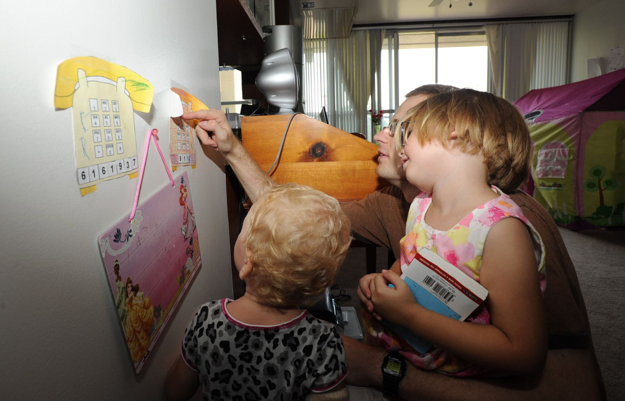 U.S. Air Force Airman 1st Class Michael Adams, 35th Civil Engineer Squadron emergency management apprentice, teaches his two daughters how to dial their home number and the emergency number, 911 at Misawa Air Base, Japan, Sept. 15, 2012. Teaching children what to do during any emergency is part of the preparation process. (U.S. Air Force photo by Airman 1st Class Kenna Jackson)