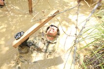 Navy Lt. Kevan Q. Lim uses a board to lift concertina wire during the endurance course at the Jungle Warfare Training Center at Camp Gonsalves Sept. 12. The endurance course is the final event of the eight-day training evolution offered at the Jungle Warfare Training Center. Lim is the chaplain for Combat Logistics Regiment 37, 3rd Marine Logistics Group, III Marine Expeditionary Force. (U.S. 