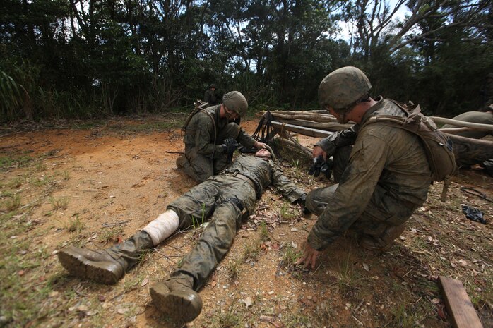 Lance Cpl. Cruze G. Parker, left, and Navy Lt. Kevan Q. Lim, right, care for Lance Cpl. Cody R. Lanier, center, acting as a simulated casualty during the endurance course as the Jungle Warfare Training Center at Camp Gonsalves Sept. 12. During the course, one member of each squad is designated as a casualty and his squad is required to carry him on a stretcher for a mile through the jungle terrain. Parker and Lanier are both airborne air delivery specialists with Combat Logistics Regiment 37, 3rd Marine Logistics Group, III Marine Expeditionary Force, and Lim is the chaplain for the regiment.