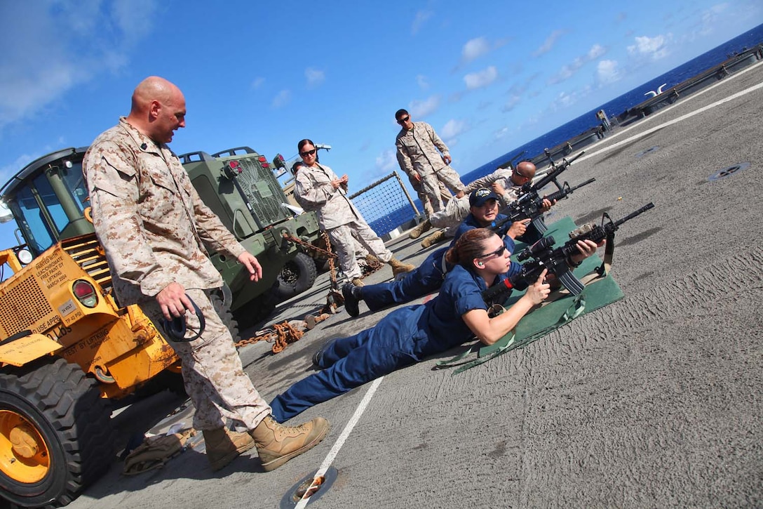 Master Sgt. Jason C. Topp, operations chief, Combat Logistics Battalion 15, 15th Marine Expeditionary Unit, coaches Petty Officer 3rd Class Erin Wolford, culinary specialist, Ship’s Company, USS Rushmore, in marksmanship principles during a live-fire rifle shoot on the flight deck of the USS Rushmore, Sept. 27. During the 15th MEU and Peleliu Amphibious Ready Group’s Western Pacific deployment, the Marines and sailors decided to let loose a few rounds in order to find their battle sight zero and ensure their M16A4 and M4A1 service rifles were functioning properly. Topp, 41, is from Marblehead, Mass. and Wolford, 25, is from Bloomingdale, Mich.