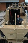 Naval Surface Warfare Center Panama City Buffalo Systems Deputy Project Engineer Steven “Tate” Carow sits near the rear-door assist mechanism. The RDA is an upgrade developed to push and hold open the rear door aboard the Marine Corps Buffalo Mine Resistant Ambush Protected vehicle. For Carow and his team, completion of this particular capability insertion helps to fulfill a critical requirement to improve crew survivability. The design uses a ruggedized motor controller, which activates a linear actuator and hydraulic cylinder. 