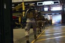 A Marine fire team sprints across a maintenance bay during a training exercise held by 2nd Maintenance Battalion, 2nd Marine Logistics Group aboard Camp Lejeune, N.C., March 27, 2013. The fire team cleared the area of enemy combatants after a simulated firefight with fellow Marines posing as terrorists. 