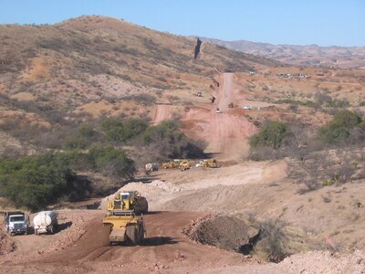 South Dakota Army National Guardsmen, supporting the Southwest Border Patrol by participating in Operation Jump Start, are continuing their assigned mission to complete the construction of a 1.5 mile section of road just east of the town of Nogales along the U.S.-Mexico border. This is a view of the 1.5 mile road project from the top side; border fence is in the top left of the photo.