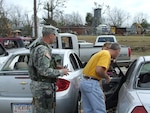 Sgt. Caleb Pope, Det. 1, Charlie Co., 1st Battalion of the 131st Armor, provides escort to parents to a vehicle that was damaged by the twister in the school parking lot.