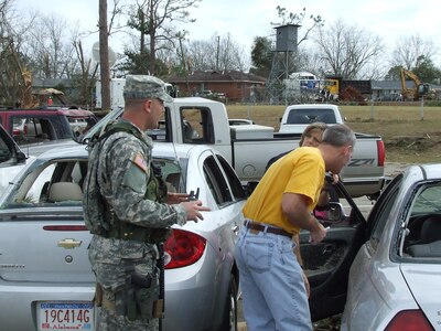 Sgt. Caleb Pope, Det. 1, Charlie Co., 1st Battalion of the 131st Armor, provides escort to parents to a vehicle that was damaged by the twister in the school parking lot.