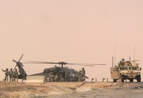 Members of the Mankato, Minn.-based 2nd Battalion, 135th Infantry Regiment survey the scene of a medical evacuation for three of their Soldiers after a Humvee in their convoy struck a pressure-plate improvised explosive device in the road Aug. 26, 2006. The IED was a 155 mm artillery shell.