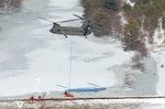A Maryland Army National Guard CH-47D Chinook helicopter from Company B, 3rd battalion, 126th Aviation Regiment, assists local authorities by hauling two giant pumps used to relieve pressure on a dam in the western Maryland town of Oakland on March 7, 2007. The dam had become dangerously full when a submerged outflow pipe had become clogged with sticks and mud placed by beavers.