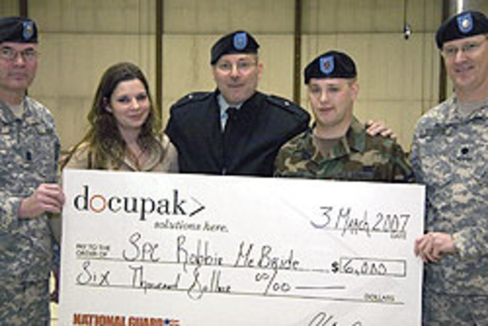 Spc. Robbie McBride (fourth from left), a member of the 237th Personnel Services Battalion, receives a ceremonial check for $6,000 for six successful enlistment referrals into the Ohio Army National Guard from Command Sgt. Maj. Bill Gilliam (far left), Ohio command sergeant major; Brig. Gen. Matthew L. Kambic (center), Ohio assistant adjutant general for Army; and Lt. Col. Steve Stivers (right), 237th PSB commander. Also pictured is McBride's wife, Carissa (second from left).