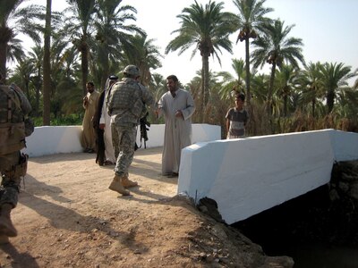 A Minnesota National Guard Soldier shakes hands with and official from Bakhan, Iraq on the newly constructed bridge to the village surrounded by canals.