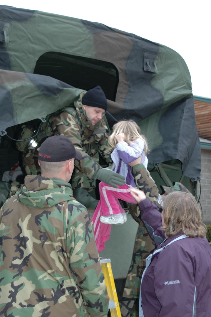 Airmen from the NH Air National Guard's 157th Air Refueling Wing assist Jordan Bell and her mother, Bev, into a five ton during a school evacuation at Nottingham Elementary School, April 16.