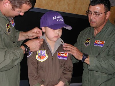 Maj. Scott Reinhold and Col. Jose Salinas pin second lieutenant rank on Dominic Magne during a commissioning ceremony in the Operations Group lounge.