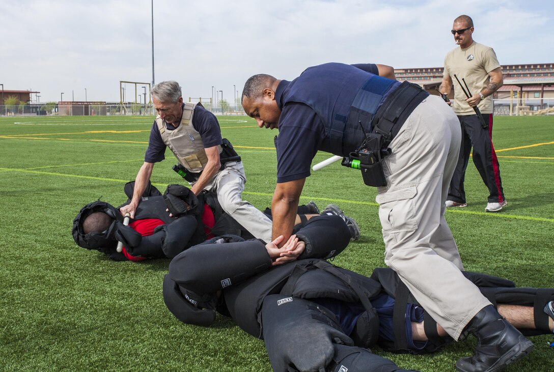 Officer Bryan Grayson, a police officer with Marine Corps Air Station Yuma’s Provost Marshal’s Office and a native of San Diego, and Officer Randy Stewart, also an officer with MCAS Yuma PMO and a native of Yuma, Ariz., subdue suspects during a live fight simulation during fight dispersion training at MCAS Yuma, March 26. This training serves to prepare officers should they need to confront a combative suspect.