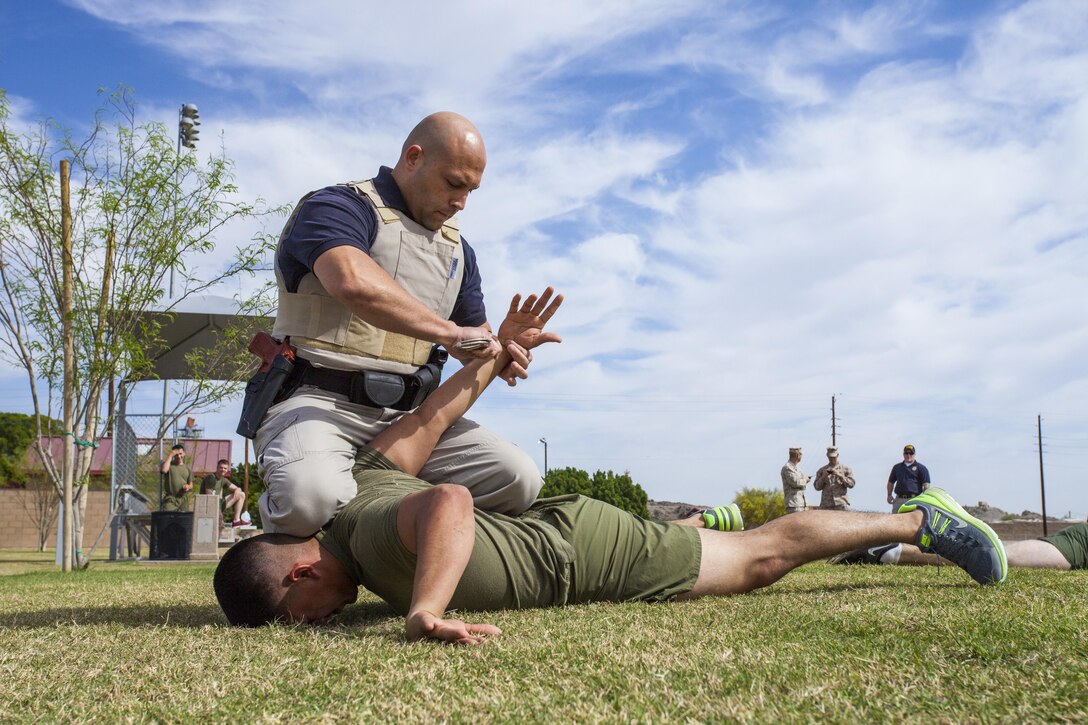 Officer Isaac Rosario, a police officer with Marine Corps Air Station Yuma’s Provost Marshal’s Office and a native of Yonkers, N.Y., handcuffs a suspect after breaking up a fight between two combatants during fight dispersion training at MCAS Yuma, March 26. This training serves to prepare officers should they need to confront a combative suspect.