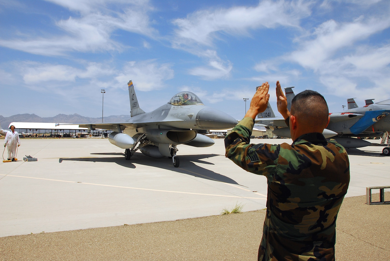 Staff Sgt. Michael Brizuela marshals the last operational F-16A model Fighting Falcon in the Air Force into a parking spot at Davis-Monthan Air Force Base, Ariz. The aircraft is being retired by the Arizona Air National Guard's 162nd Fighter Wing which now flies the more modern F-16C and F-16D models. This aircraft and two F-16Bs being retired will be stored at the Aerospace Maintenance and Regeneration Group at Davis-Monthan.