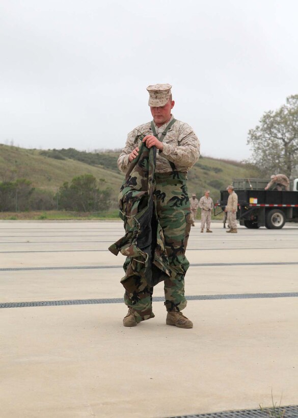 Cpl. Ronald Isaacs, 24, from Bluff City, Tenn., a chemical, biological, radiological, nuclear defense chief with 9th Communication Battalion, I Marine Expeditionary Force, puts on a Mission Oriented Protective Posture suit to prepare for the gas chamber at Camp Pendleton, Calif., March 26. The gas chamber is required annual training for Marines.