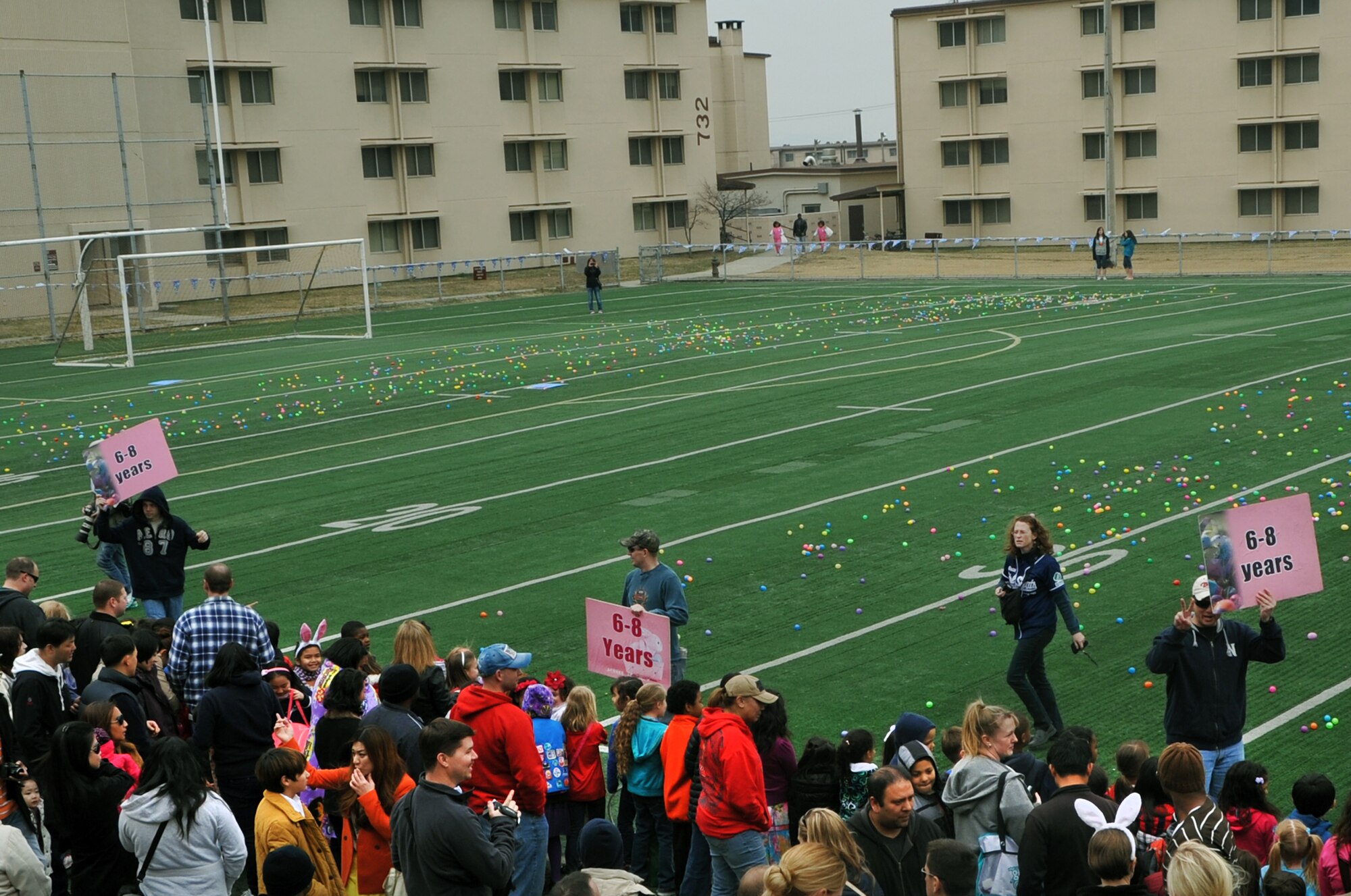 Volunteers hold up signs to direct children to their designated age groups for the Easter Egg Hunt at the Osan High School football field on Osan Air Base, Republic of Korea, March 30, 2013. More than 200 participants attended in the event. (U.S. Air Force photo/Senior Airman Kristina Overton)