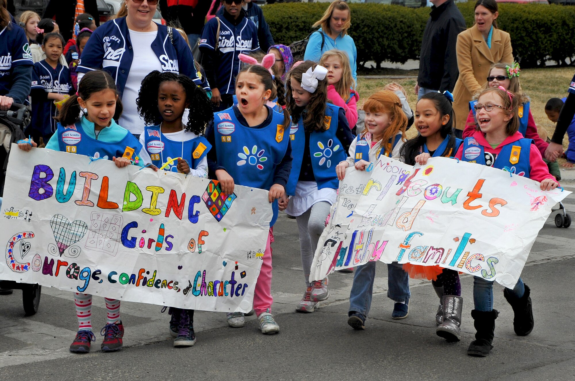 The Osan Girl Scout troop carries their banner and sings songs while marching in the Child Abuse Prevention Month Parade on Osan Air Base, Republic of Korea, March 30, 2013. The parade started at the officers’ club and finished at the Osan High School football field. (U.S. Air Force photo/Senior Airman Kristina Overton)