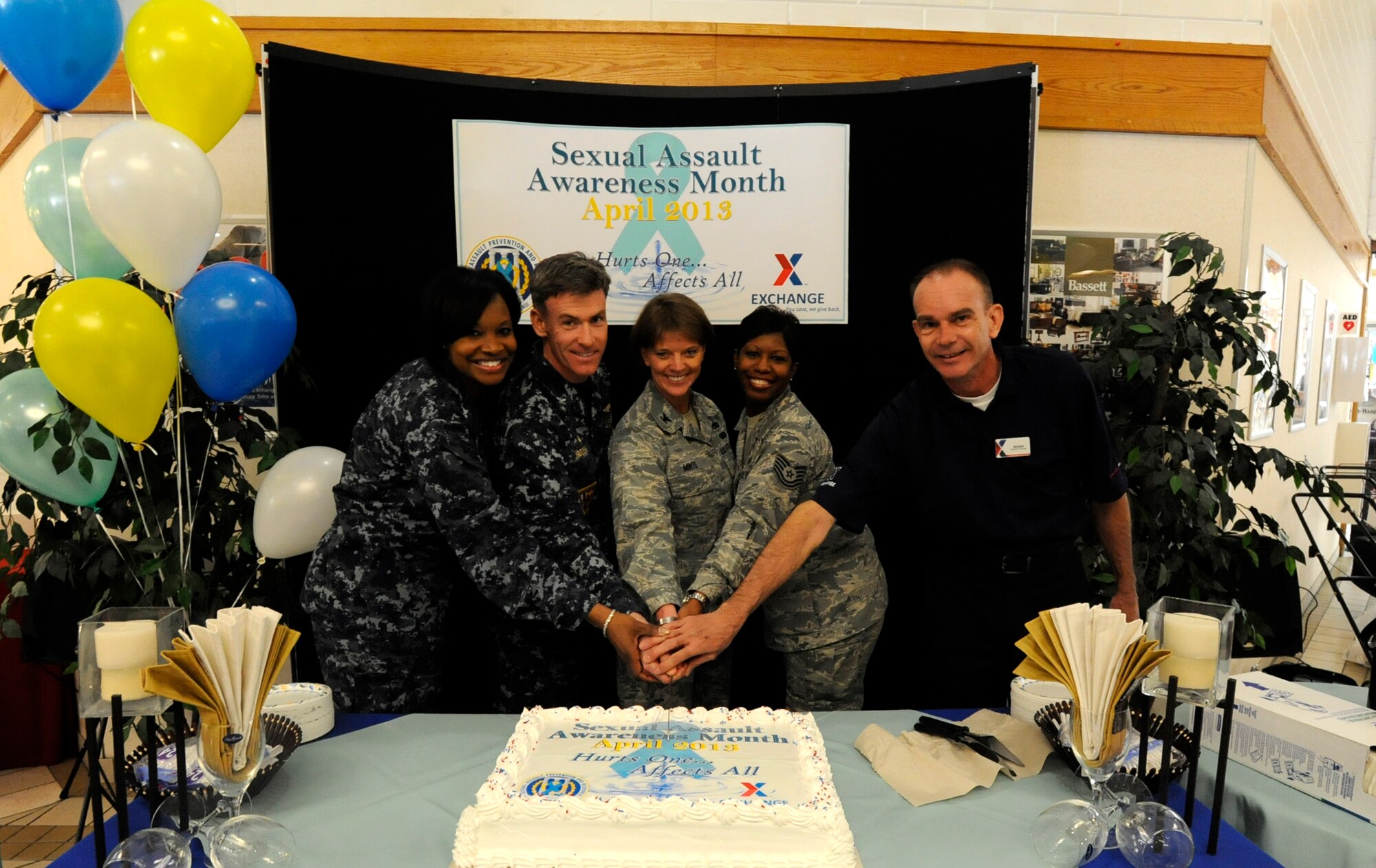 Members of the U.S. Air Force, Navy and the Army, Air Force Exchange Service cut the cake during the opening ceremony of the Sexual Assault Awareness Month campaign in the exchange foyer at Misawa Air Base, Japan, April 1, 2013. This month’s theme “Hurts one. Affects all,” was designed to express how sexual assault affects the military as a whole and not just one individual. (U. S. Air Force photo by Airman 1st Class Kenna Jackson)