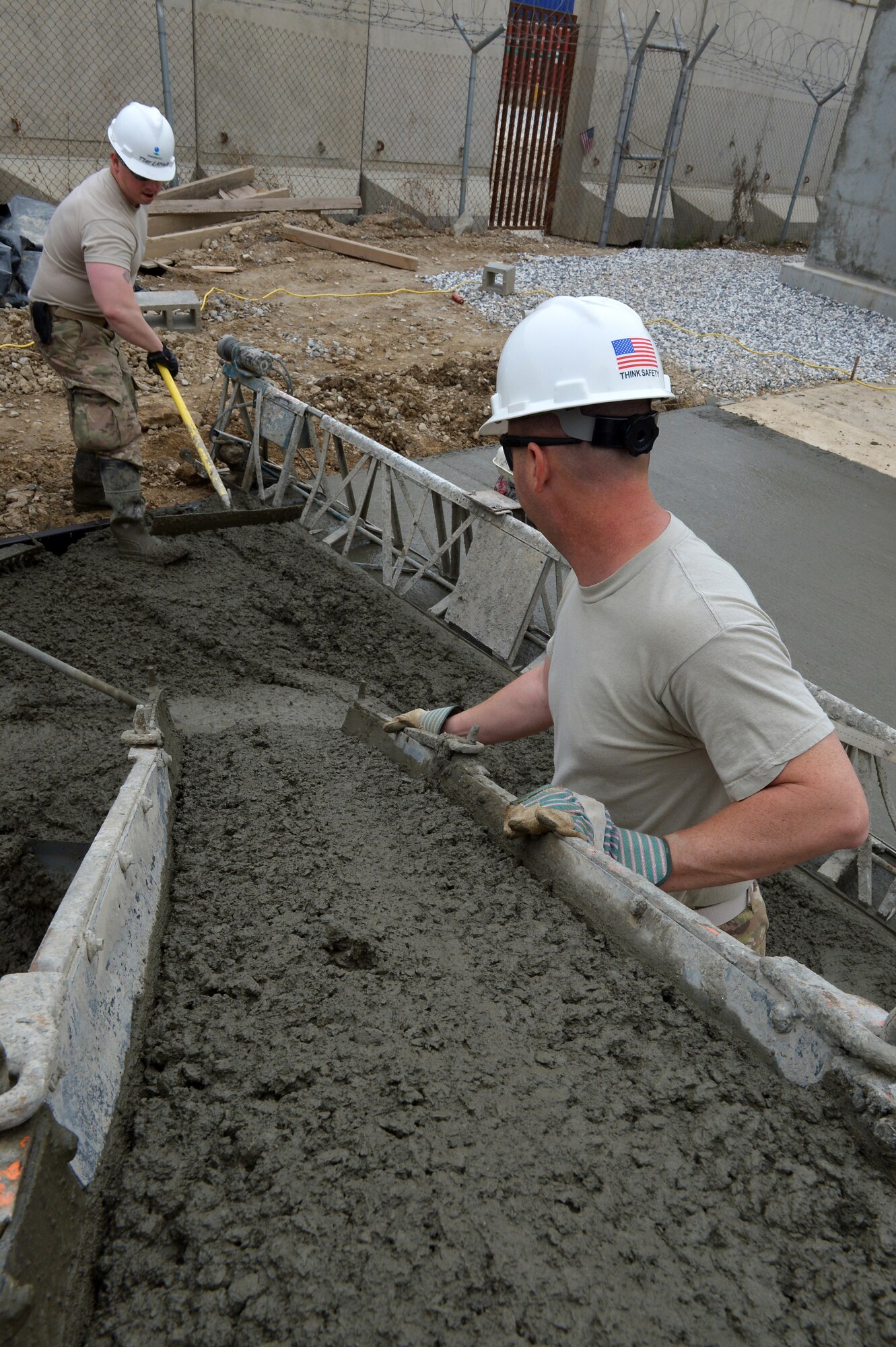 Tech. Sgt. Dana LaPlante (left) and Staff Sgt. Shane Helms, 455th Expeditionary Civil Engineer Squadron heavy equipment operators, spread concrete during a project on Bagram Airfield, Afghanistan, March 27, 2013. The 455th ECES are responsible for supporting the BAF flightline through various projects, including creating berms for ammunition depots and digging trenches for power lines or drainage. (U.S. Air Force photo/Senior Airman Chris Willis)