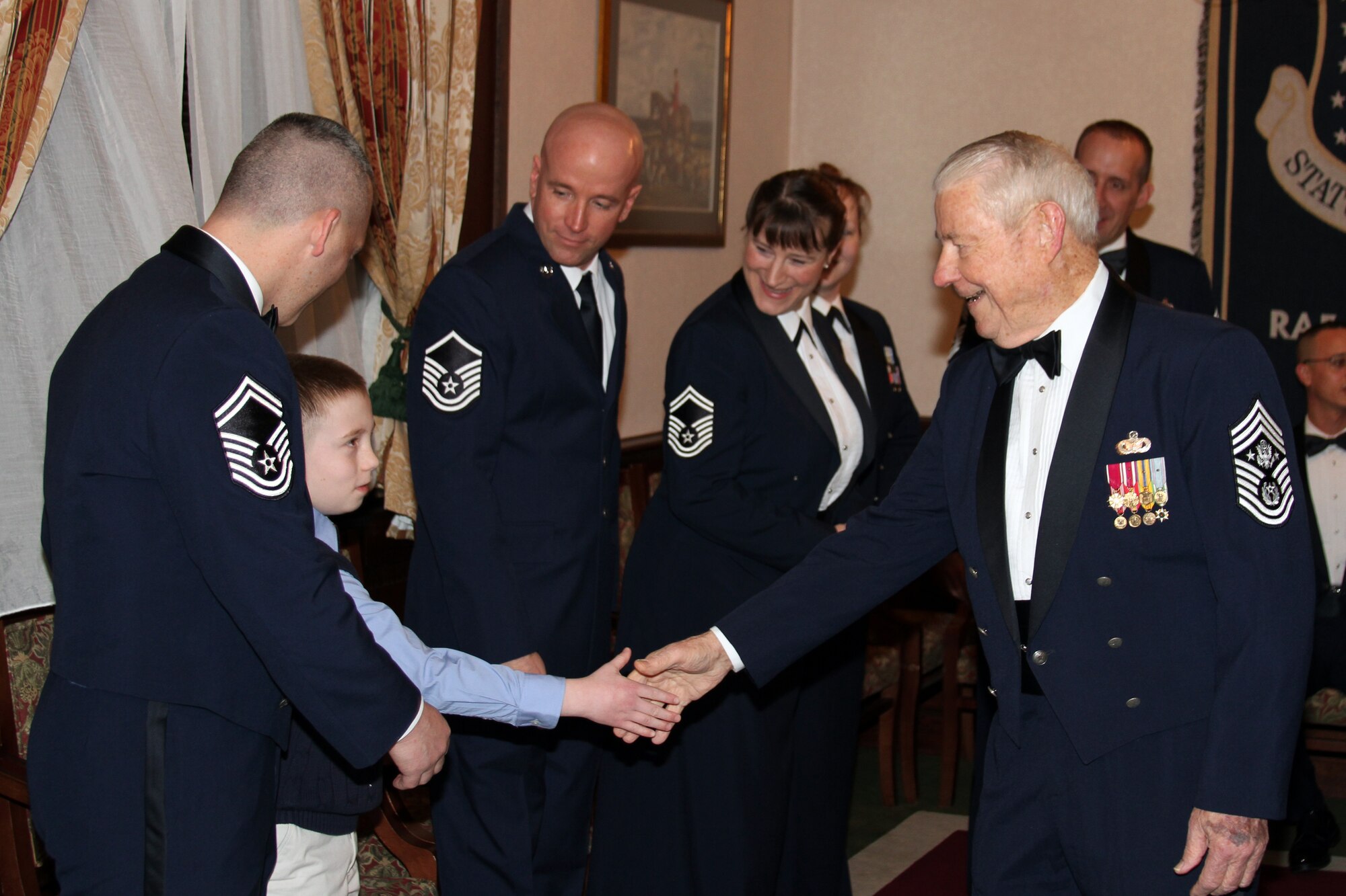 RAF LAKENHEATH, United Kingdom – Senior Master Sgt. Gene Eastman, 501st CSW Regional Contracting Office chief, and his son Alex, meet retired Chief Master Sgt. of the Air Force Robert Gaylor, the fifth Chief Master Sergeant of the Air Force, during a Chief Master Sergeant Recognition Ceremony at RAF Lakenheath’s Eagles' Landing March 9. Retired Chief Master Sgt. of the Air Force Gaylor was the guest speaker of the ceremony. (Courtesy photo)