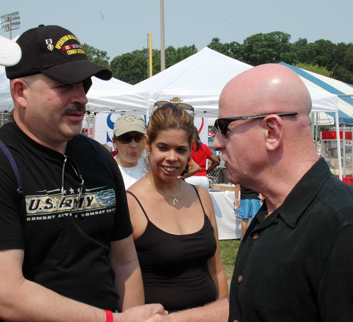 LTG H Steven Blum, chief of the National Guard Bureau, greets Sgt. Luis Martinez (left) and Martinez's wife, Sylvia, at the National Guard Bureau Picnic held Aug. 15 in Woodbridge, Va. Martinez, whose left eye cornea and lens were destroyed on April 22 by a penetrator device explosion, was one of 27 National Guard Wounded Warriors from Walter Reed Army Medical Center who attended the event.