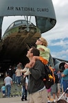 Two of the visitors to the Air Force Week New England "Wings of Hope"  Air Show at Pease Air National Guard Base in Portsmouth, N.H., watch a stunt glider pilot Aug. 19 in front of a New York Air Guard C-5 Galaxy.