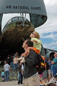 Two of the visitors to the Air Force Week New England "Wings of Hope"  Air Show at Pease Air National Guard Base in Portsmouth, N.H., watch a stunt glider pilot Aug. 19 in front of a New York Air Guard C-5 Galaxy.