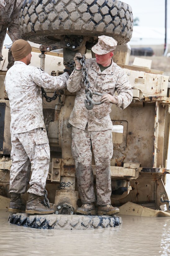 Marines from 2nd Maintenance Battalion, Combat Logistics Regiment 25, 2nd Marine Logistics Group place chains on a Mine Resistant Ambush Protected vehicle during the Vehicle Recovery Course aboard Camp Lejeune, N.C., March 25, 2013.The four week course teaches Marines how to recover vehicles using crane operations, retrieval systems and a lift tow. 