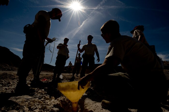 RED HORSE members, measure the depth of a borehole at the 820th RED HORSE rock quarry, March 28, 2013, at Nellis Air Force Base, Nev. The 820th RED HORSE special capabilities program holds four classesa year teaching basic introduction to explosives and quarry blasting for heavy equipment operators assigned to RED HORSE. (U.S. Air Force photo by Airman 1st Class Christopher Tam)