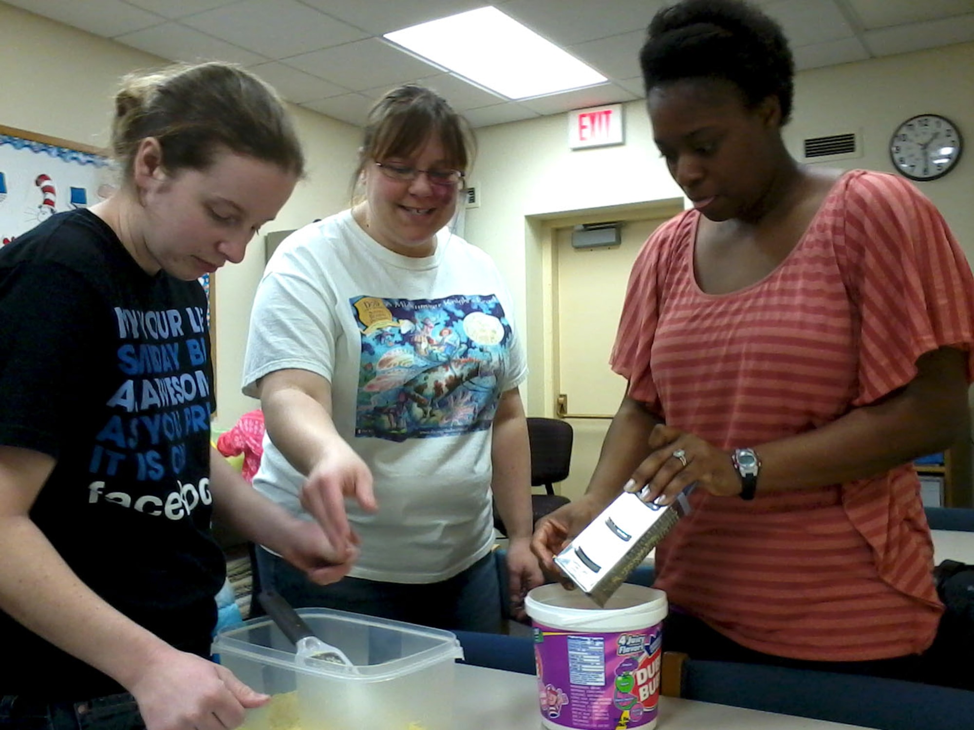 Stacie Collins, do-it-your-self instructor, thanks Kayla Barclay and CeeCee Long, for volunteering to scrape bars of soap used to create laundry detergent during a do-it-yourself event hosted March 29, 2013, at the Grand Forks Air Force Base Library. (U.S. Air Force photo/Staff Sgt. Luis Loza Gutierrez)
