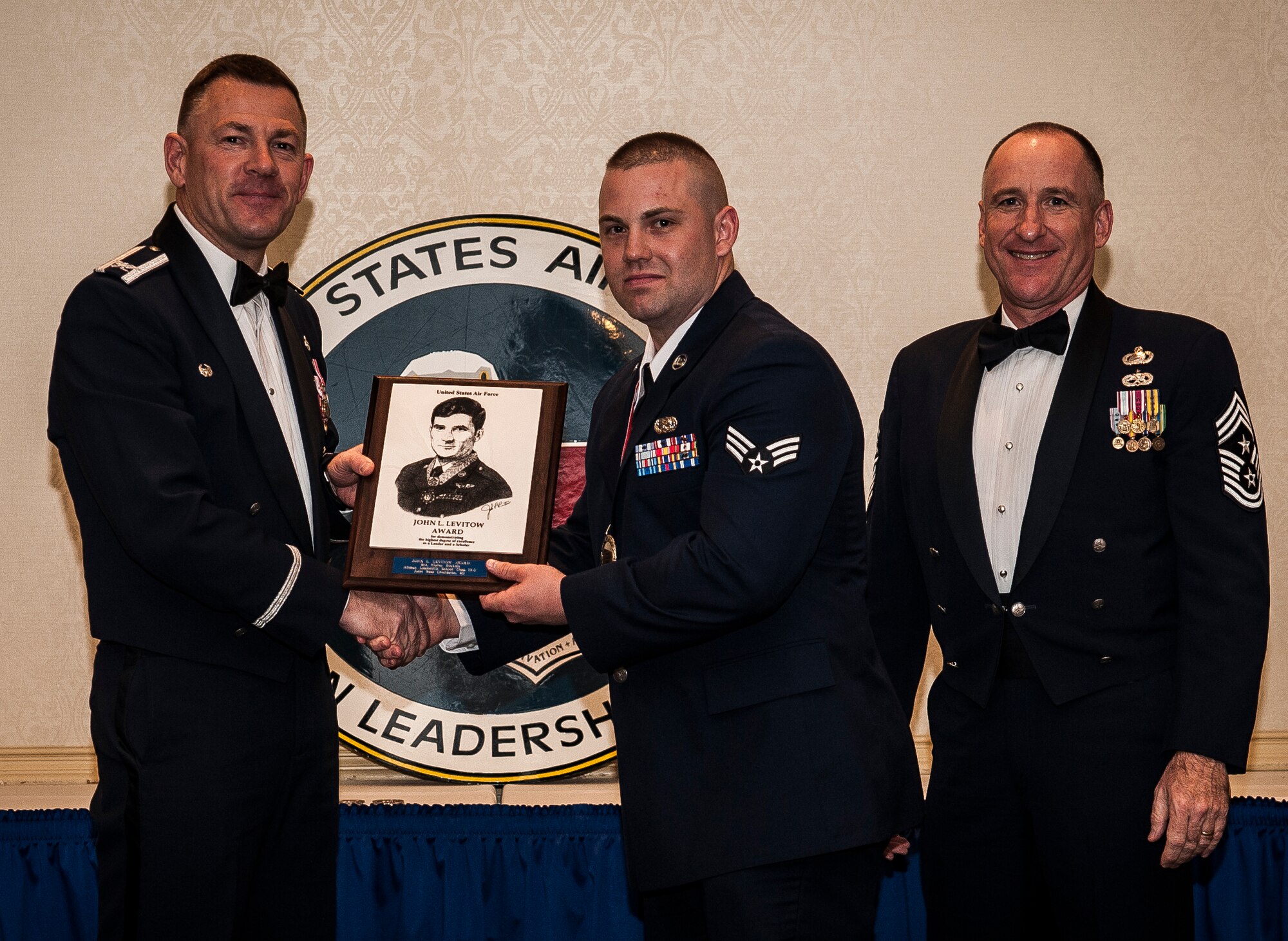 Col. Richard McComb, Joint Base Charleston commander, and Chief Master Sgt. Al Hannon, 628th Air Base Wing command chief, present the John L. Levitow Award to Senior Airman Wesley Stickels, from the 628th Logistics Readiness Squadron, during the Airman Leadership School Class graduation March 28, 2013, at Joint Base Charleston - Air Base, S.C. The Levitow award is given for a student's exemplary demonstration of excellence, both as a leader and a scholar. (U.S. Air Force photo/ Senior Airman Dennis Sloan)