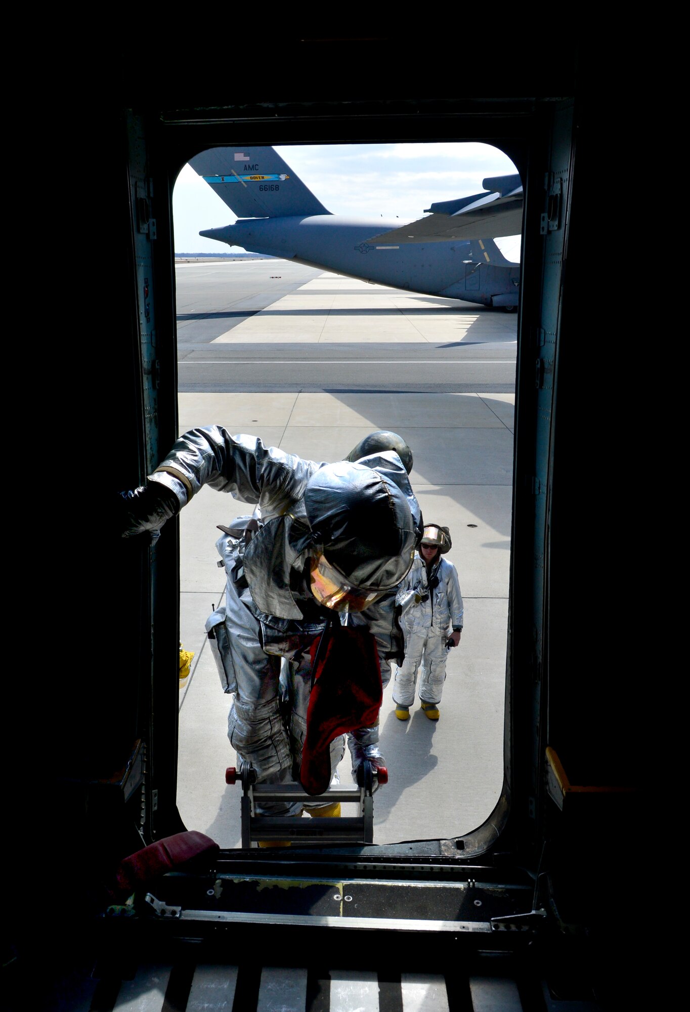 A firefighter with the 436th Civil Engineer Squadron fire department climbs into a C-5M March 29, 2013, at Dover Air Force Base, Del. The fire department was practicing emergency aircrew retrieval and firefighting. (U.S. Air Force photo/David Tucker)