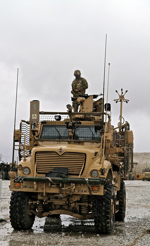 Spc. Koffi Assila, a cargo specialist and native of Africa, mounts the .50-caliber machine gun prior to the start of their mission from Bagram Air Field to Forward Operating Base Fenty. His job requires him to maintain constant eyesight on the road, the debris and trash, the caves in the mountains and the rooftops of houses. (U.S. Army photo by Sgt. V. Michelle Woods/Released)
