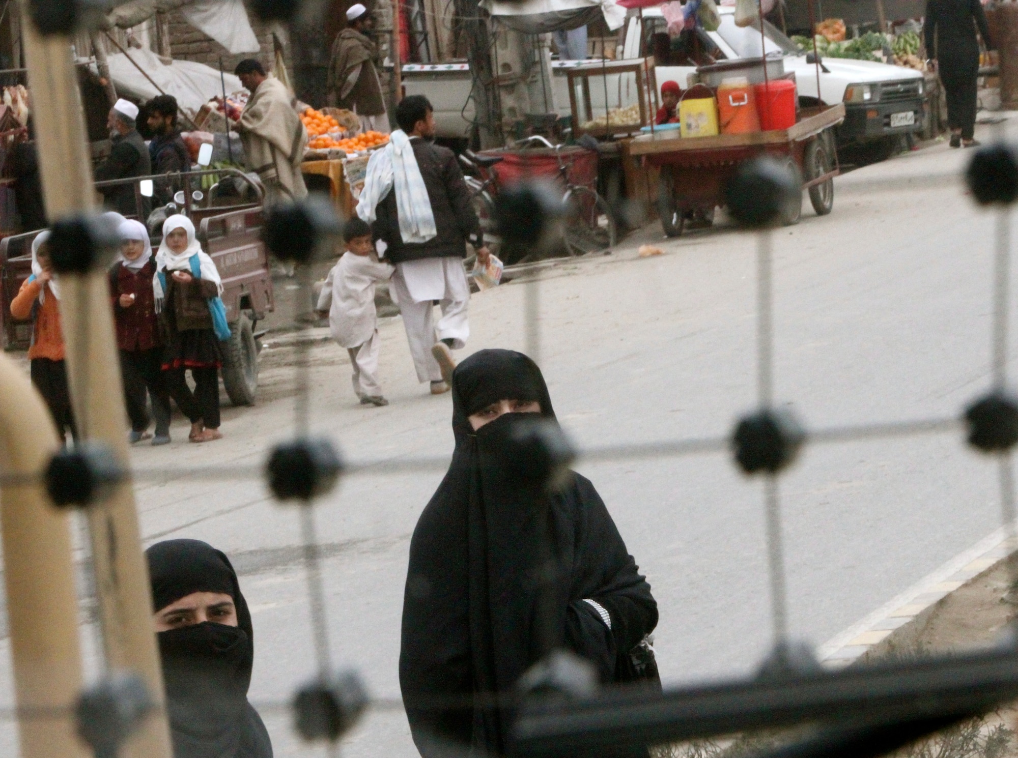 Women draped in burqas, traditional Islamic clothing which covers the body from head to toe, watch as the “Dark Side” Convoy Escort Team, 359th Inland Cargo Transfer Company, escort a convoy of 30 trucks through Jalalabad, Afghanistan Feb. 25, 2013. (U.S. Army photo by Sgt. V. Michelle Woods/Released)
