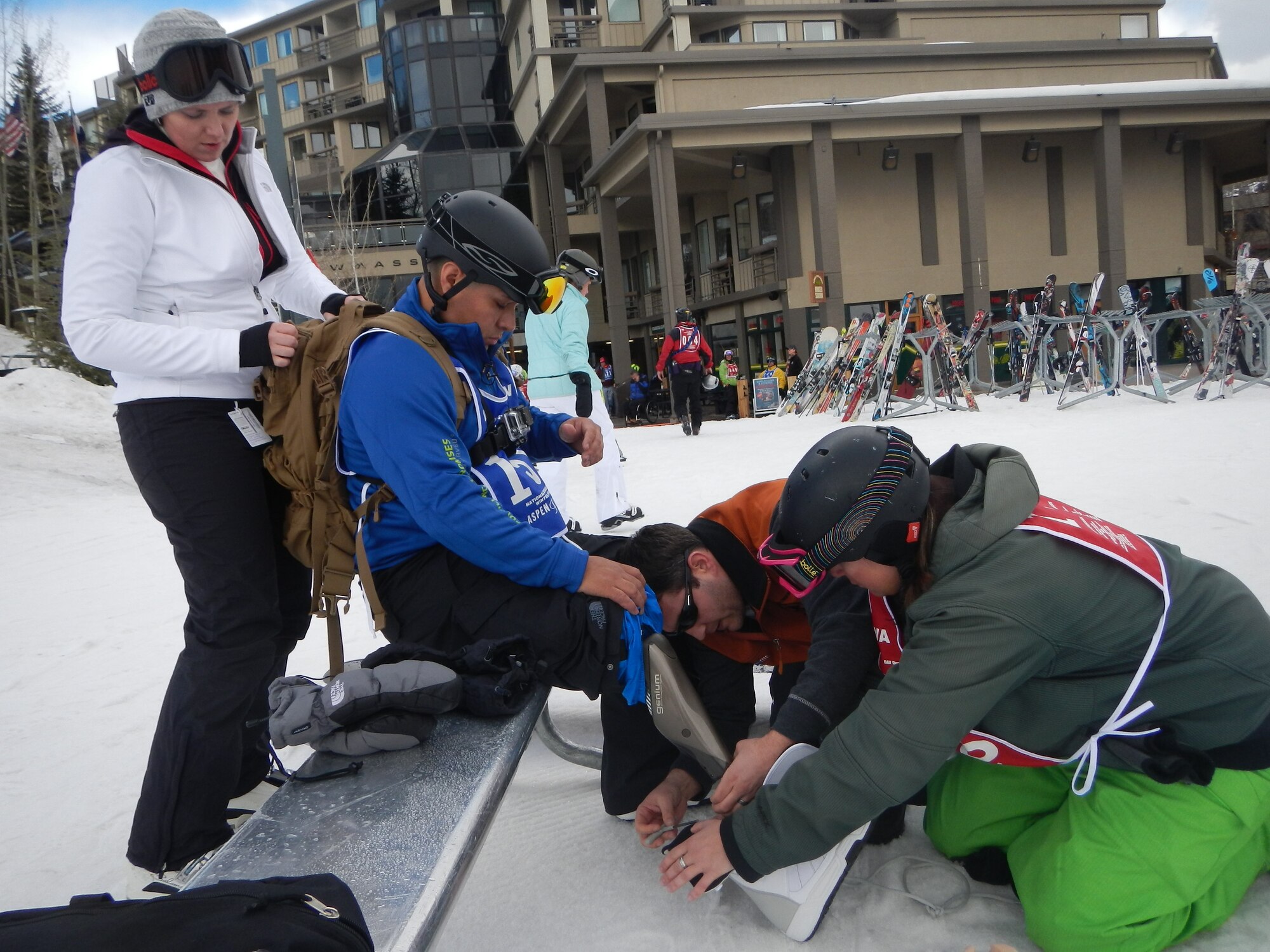 Army Sgt. Kristian "Dino" Cedeno, center, who was severely wounded in Afghanistan, gets his ski boots adjusted by adaptive ski instructor Jill Reifsnider, right, and another instructor at the National Disabled Veterans Winter Sports Clinic at Snowmass Mountain, Colo., April 1, 2013, as his wife, Gwen, left, looks on. Cedeno snowboarded at the clinic for the first time since being wounded. (Department of Defense photo by Donna Miles) 