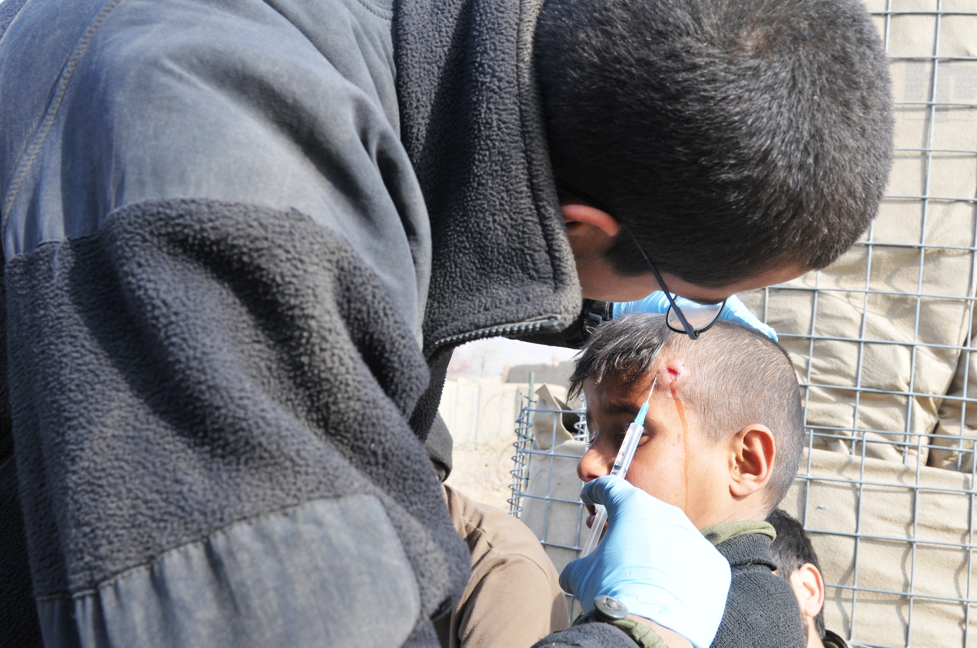BALA MURGHAB, Afghanistan – U.S. Army Spc. Oscar Castro, White Platoon, Bulldog Troop medic, deployed from 1st Brigade, 4th Infantry Division at Fort Carson, Colo., applies anesthetic to 10-year-old Abdul Hagh's head at Combat Outpost Delorean, Bala Murghab, Badghis province, Afghanistan, Jan. 8, 2011. When the White Platoon soldiers weren't involved in kinetic activities, they performed counter-insurgency operations, development initiatives, and sometimes administered medical aid to the local population. (U.S. Air Force photo/Master Sgt. Kevin Wallace/RELEASED)