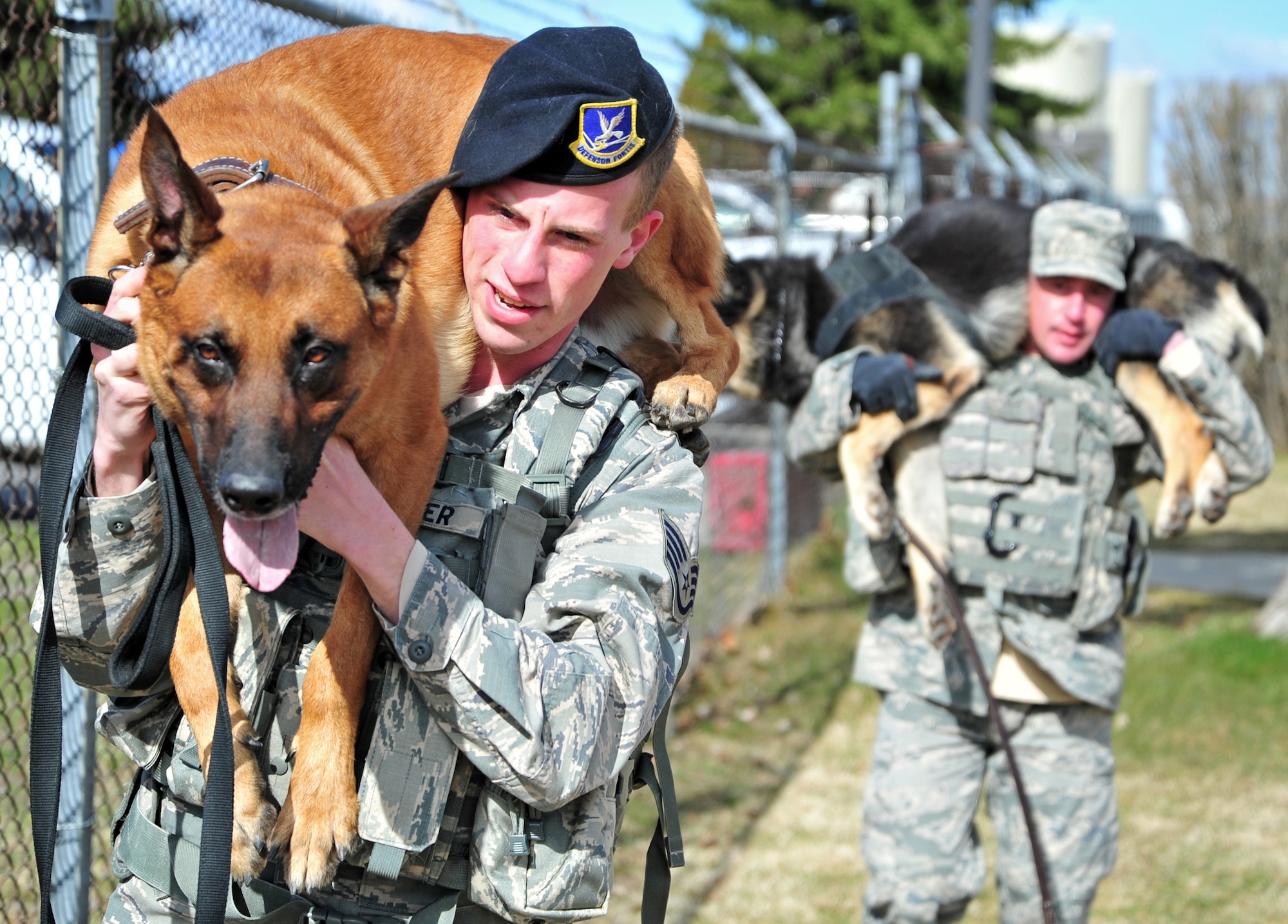 92nd Security Forces Squadron military working dog handlers display an over-the-shoulder carry with their K-9’s during a training session at Fairchild Air Force Base, Wash., March 21, 2013. The purpose of the carry is to keep the dog from being exhausted if it’s in need of medical care. (U.S. Air Force photo by Senior Airman Taylor Curry)