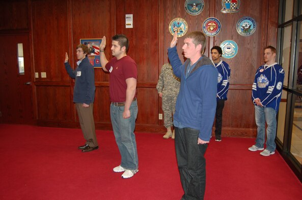 Syracuse Crunch professional hockey players J.T. Brown and Matt Taomina (behind right) observe enlistment oath ceremony at Syracuse Military Entrance Processing Station (MEPS) located on Hancock Field Air National Guard Base, Syracuse, New York.  The Syracuse MEPS is responsible for processing all applicants for enlistment into the Armed Forces between Buffalo and Albany.  It is one of a network of 65 MEPS located across the country. (Photo by Paul J. Salvatore/Released).
